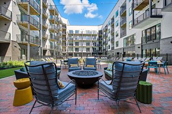 A patio with chairs and a table in front of apartment buildings.